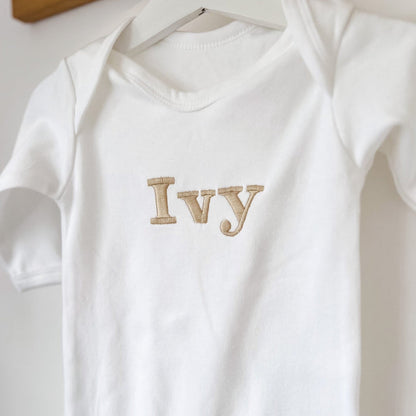 White baby romper close-up with “Ivy” embroidered name on the front.