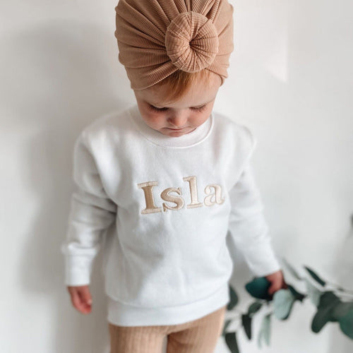 White crewneck sweater with long sleeves, front print reading “Isla”