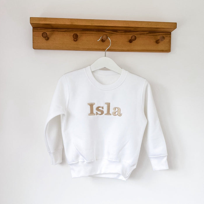 White crewneck sweatshirt with “Isla” printed on chest
