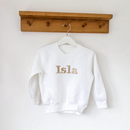 White crewneck sweatshirt with “Isla” printed on chest