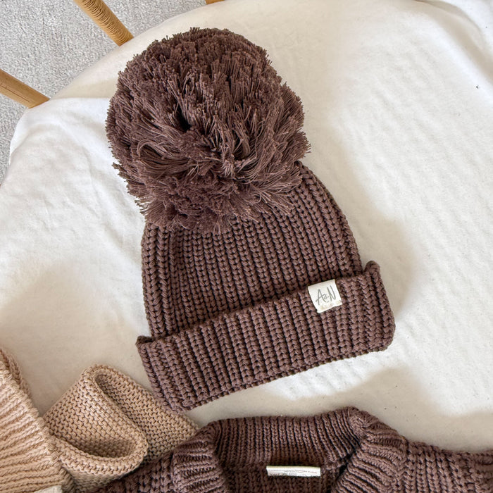 Brown knitted baby beanie with chunky ribbed cuff and large pom-pom