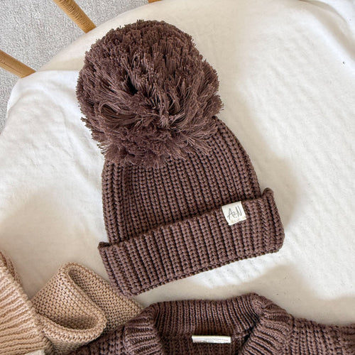 Brown knitted baby beanie with chunky ribbed cuff and large pom-pom