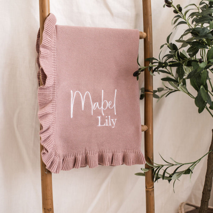 Dusty pink knit blanket with frilled edge and “Mabel Lily” name embroidery