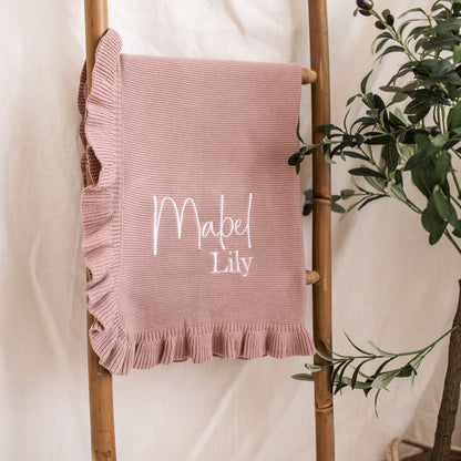 Dusty pink knit blanket with frilled edge and “Mabel Lily” name embroidery