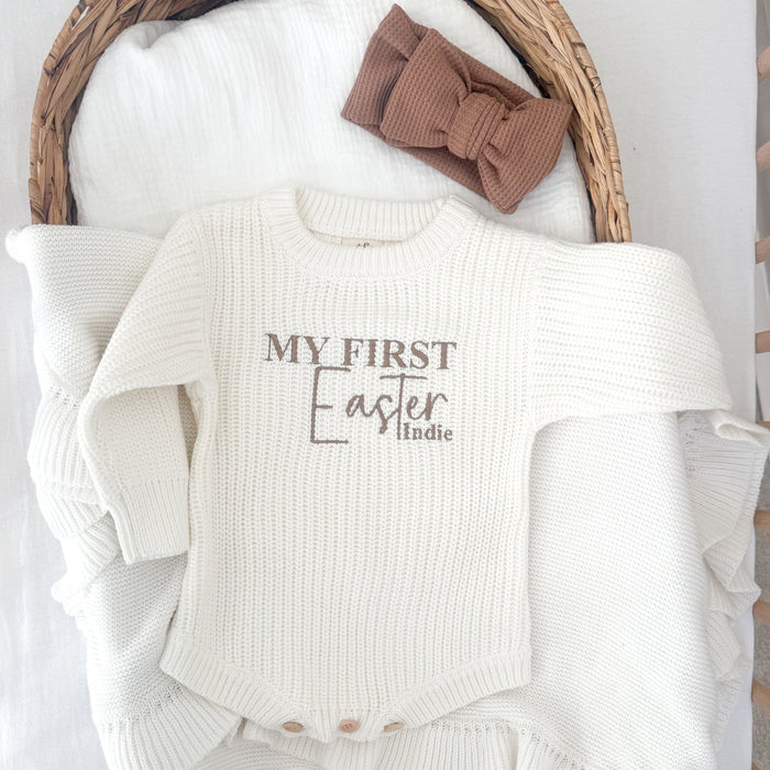 White knitted baby romper with 'My First Easter' and 'Indie' text, long sleeves