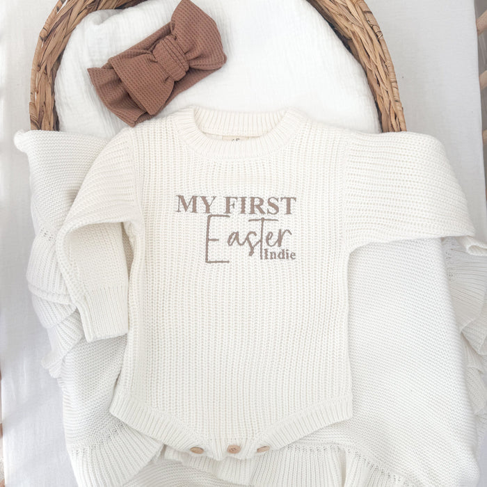 White knitted baby romper with 'My First Easter' and 'Indie' front panel, ribbed cuffs