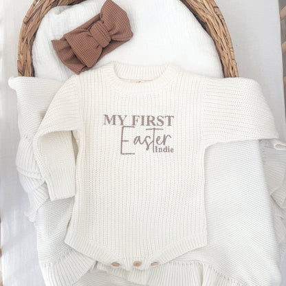 White knitted baby romper with 'My First Easter' and 'Indie' front panel, ribbed cuffs