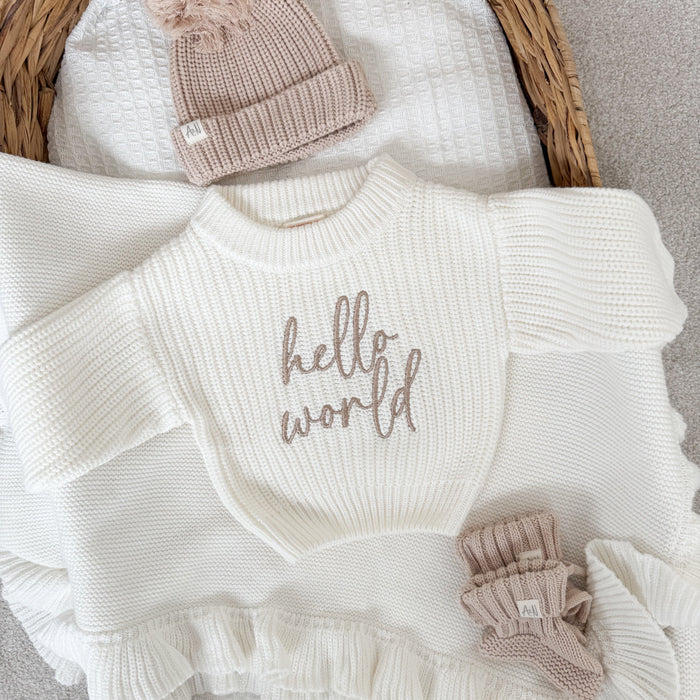 White knit jumper with ribbed crew neck, ruffled hem, and 'hello world' print