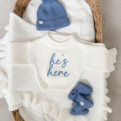 White chunky knit jumper with crew neck, blue 'he's here' print, ruffled cuffs