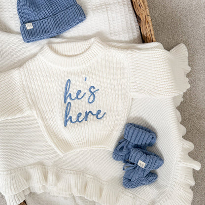White chunky knit jumper with crew neck, blue 'he's here' print, ruffled hem