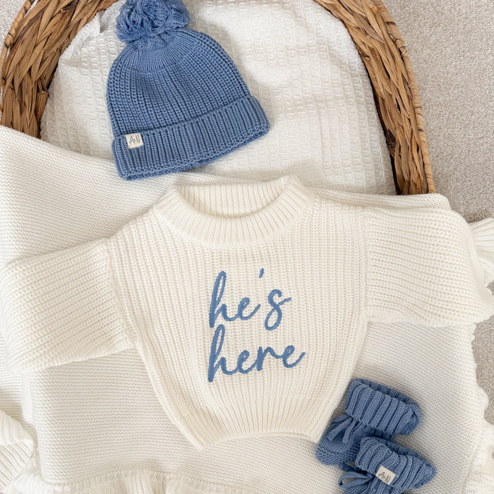 White chunky knit jumper with blue 'he's here' front print, ribbed crew neck
