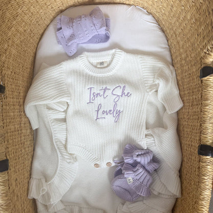 Cream knitted romper, short sleeves, script 'Isn't She Lovely', and purple bow