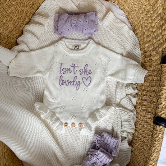 White knit romper with lavender panel and bow accents, ruffled hem and short sleeves
