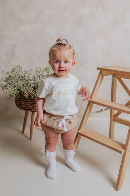 Ivory script-name toddler T-shirt with gold lettering, short sleeves
