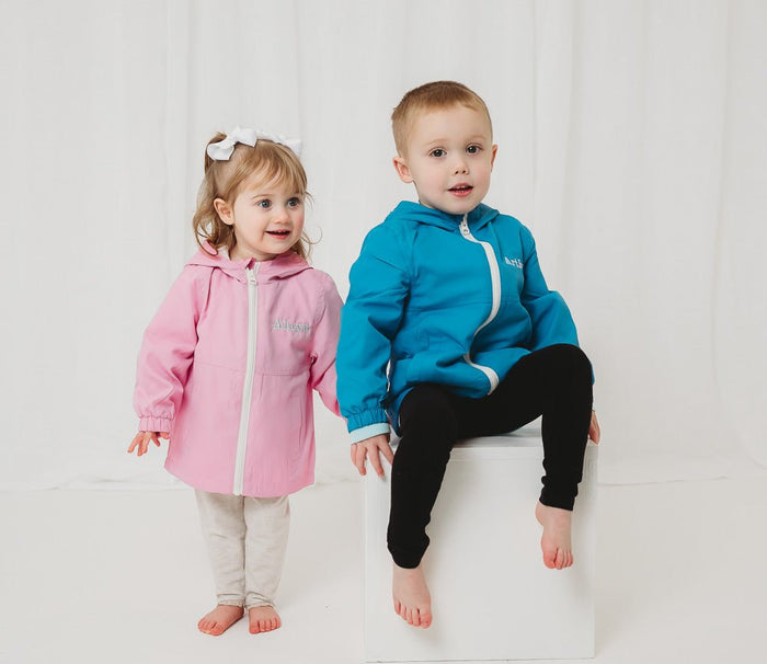 Pink and blue lightweight rain coats with hoods and front zips, elastic cuffs
