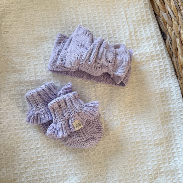 Lilac knitted baby booties with ruffled ankle cuffs and small logo patch