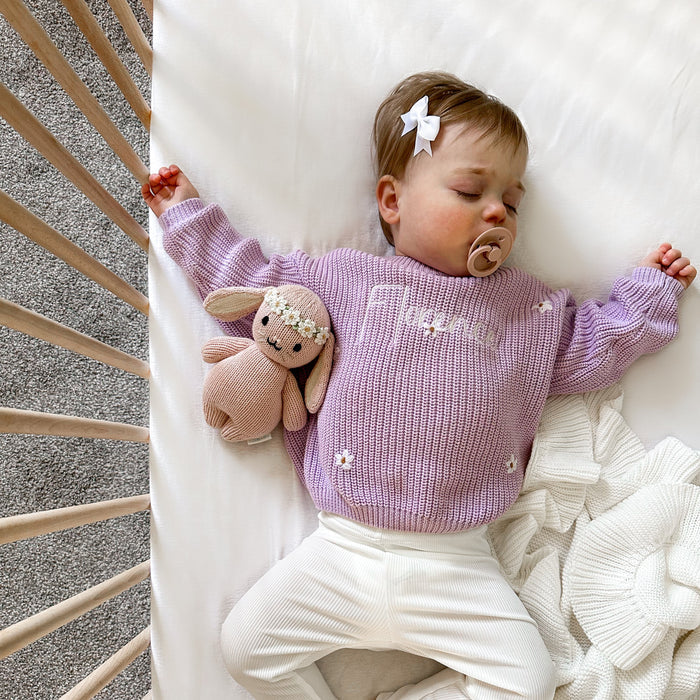 Lilac knitted baby jumper with embroidered script and small floral motifs on chest