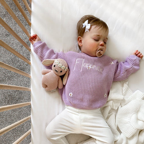 Lilac knitted baby jumper with embroidered script and small floral motifs on chest