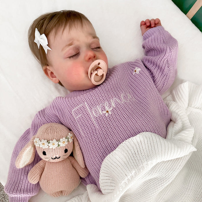 Lilac knitted baby jumper with embroidered script on front and floral motifs on sleeves