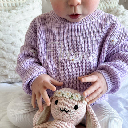Lilac knitted baby jumper close-up with embroidered script and small floral embellishments