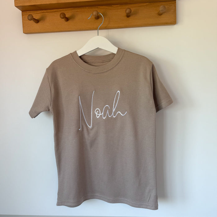 Taupe short-sleeve T-shirt with white cursive name print, crew neckline