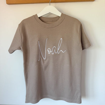 Taupe short-sleeve T-shirt with white cursive name print on the chest