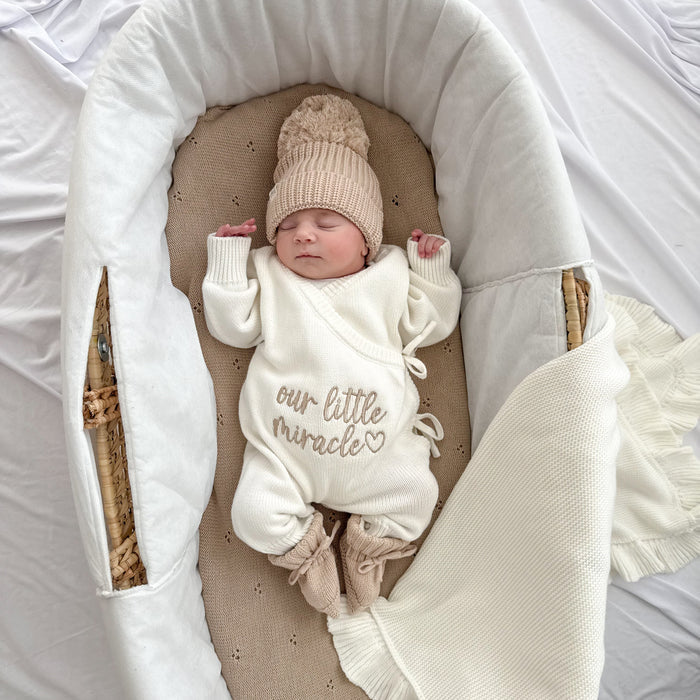 Cream long-sleeve baby romper with drawstring ties and “our little miracle” text