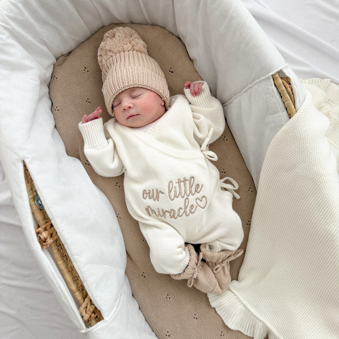 Cream long-sleeve baby romper with “our little miracle” print and cuffed knit legs