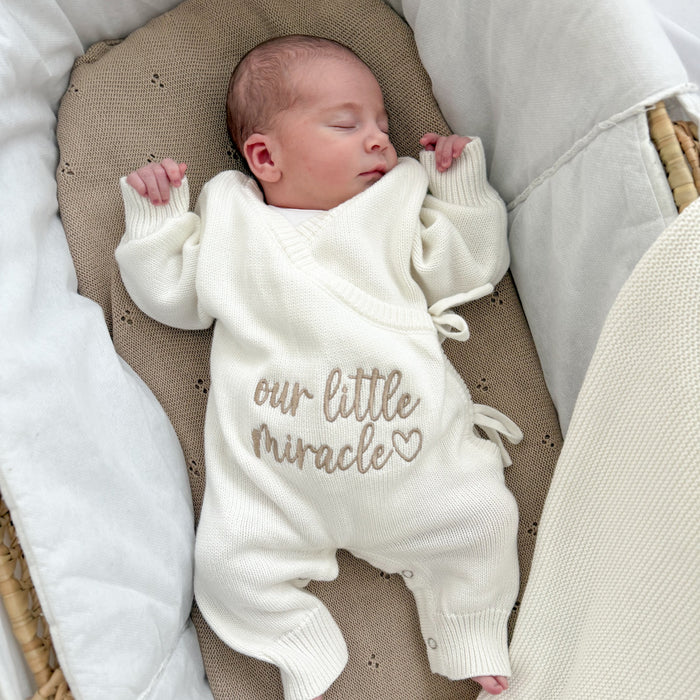 Cream long romper with “our little miracle” print, long sleeves and tie closures