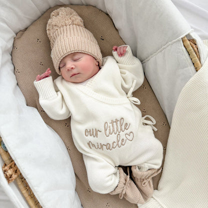 Cream long-sleeve baby romper with “our little miracle” text and drawstring neck ties