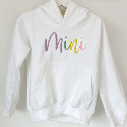 Close-up white hoodie with 'Mini' script embroidery on chest and kangaroo pocket