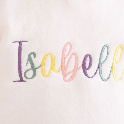 Multicolor embroidered Isabela text on white fabric