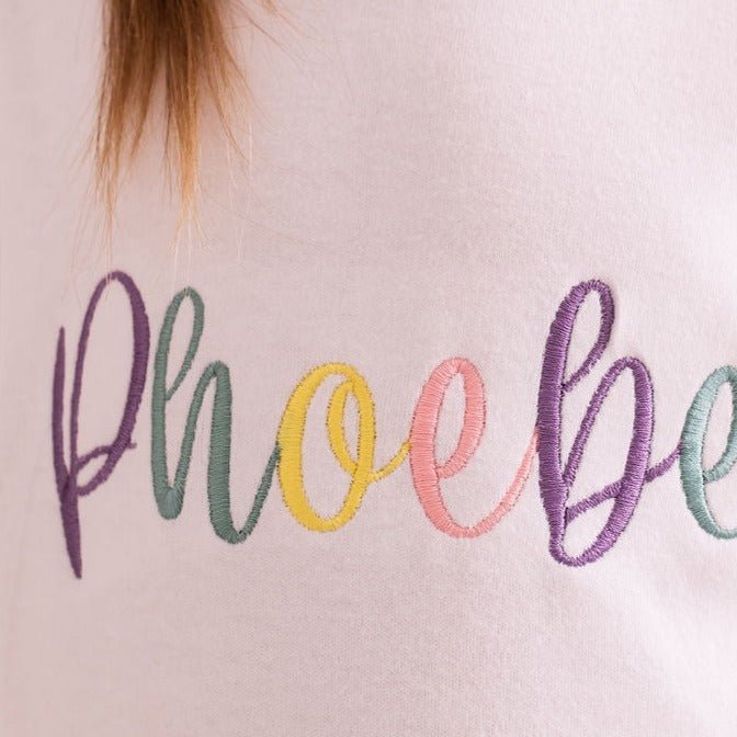Close-up of pastel script embroidery on a white T-shirt front