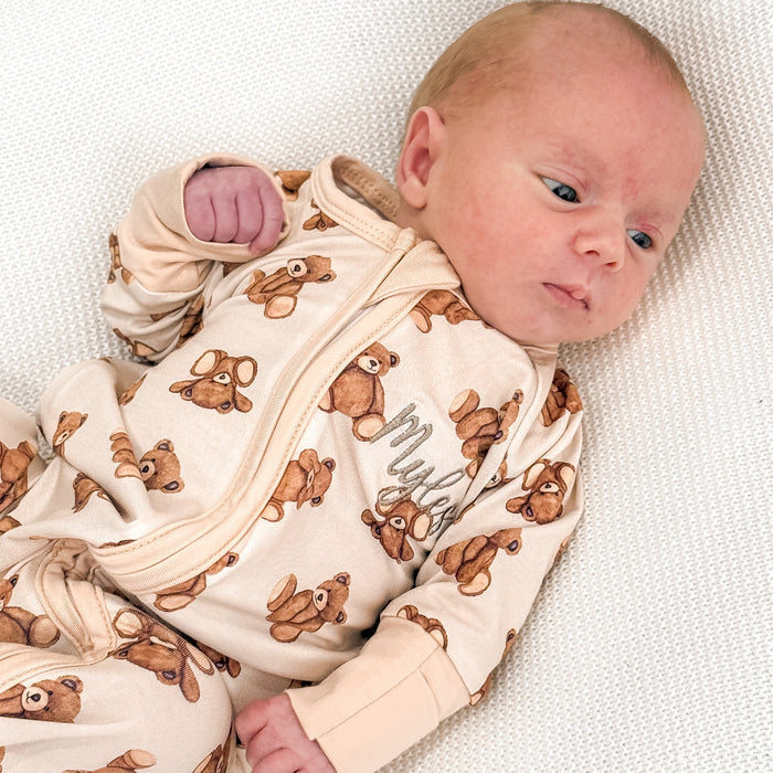 Baby zip sleepsuit with teddy bear print, zip front and ribbed cuffs; on infant.