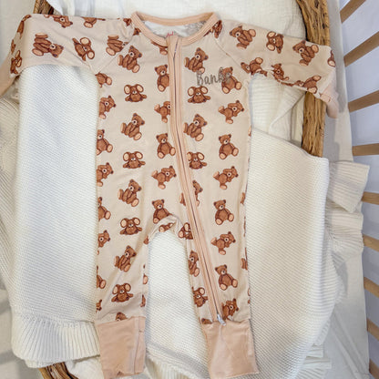 Baby zip sleepsuit with brown teddy bear print on light cream footed style.