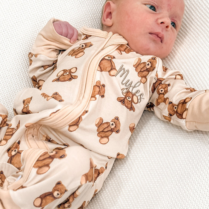 Baby zip sleepsuit with teddy bear print, zip front and long sleeves on infant.
