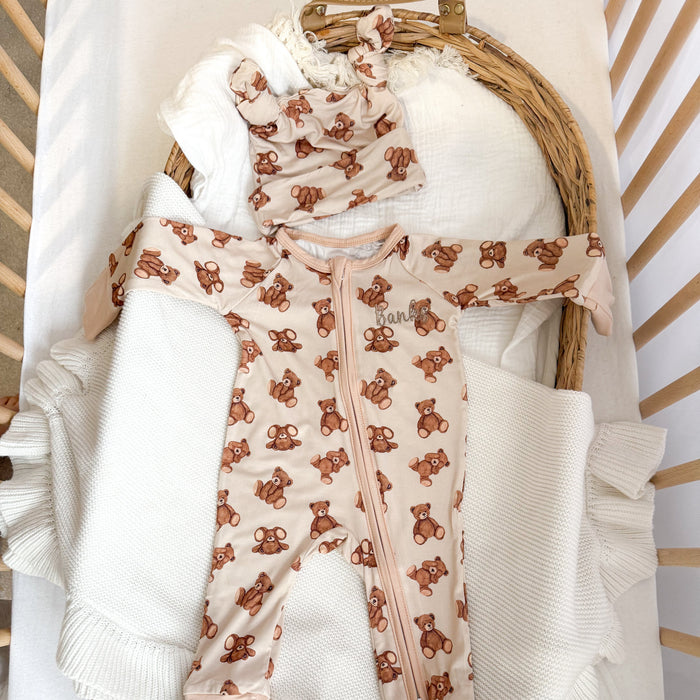 Baby zip sleepsuit in basket, teddy bear print on cream with long zip front.