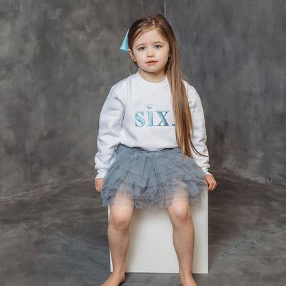White kids birthday age sweater with light blue "six" graphic, crew neck, long sleeves