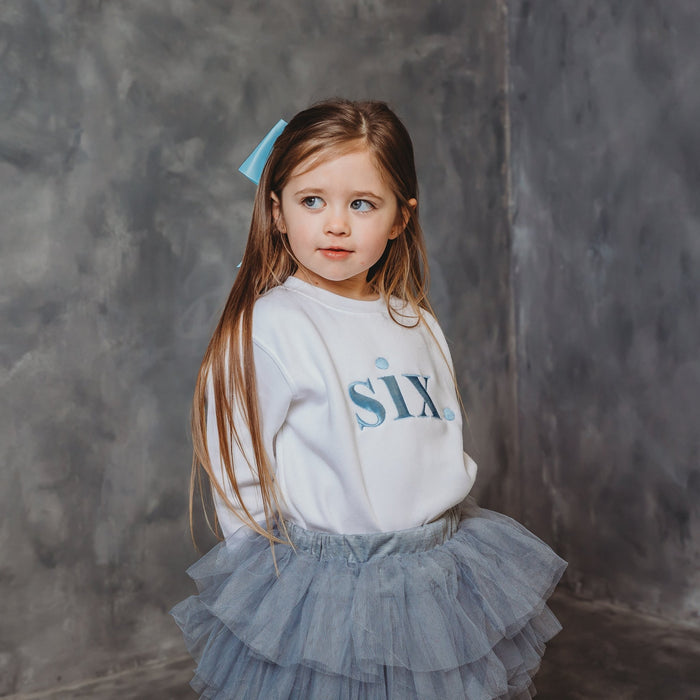 White kids birthday age sweater with light blue "six" print and long sleeves