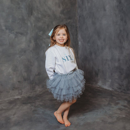 White kids birthday age sweater with light blue "six" front print and long sleeves
