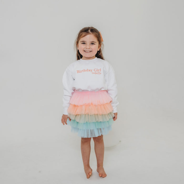White kids sweater with Birthday Girl text graphic in pink and gold