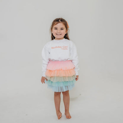 White kids sweater with Birthday Girl text graphic in pink and gold