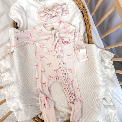 White ribbed zip sleepsuit with pink bow pattern, footed legs and 'Opal' chest print