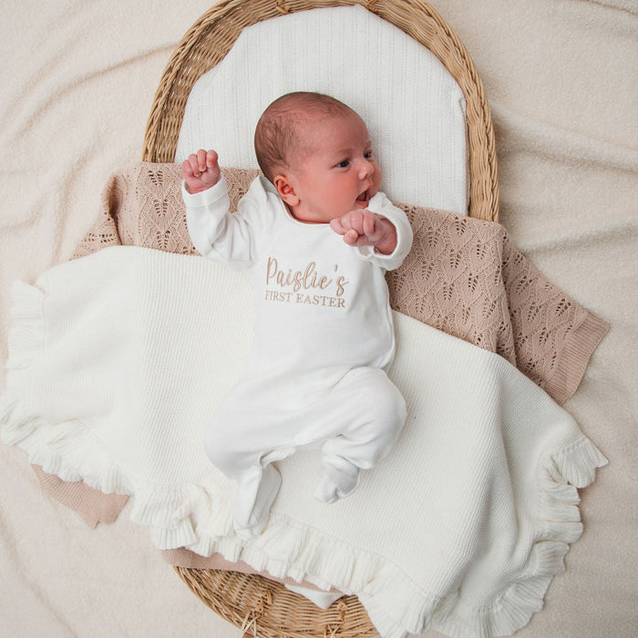 Baby wearing personalised first Easter sleepsuit in white, 'Paislie's First Easter' print