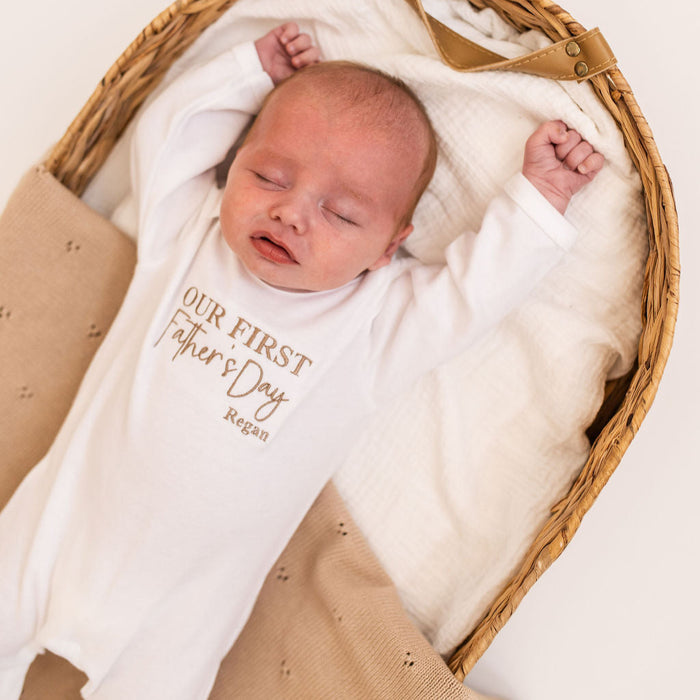 White baby sleepsuit with long sleeves, 'Our First Father's Day' text and Regan name