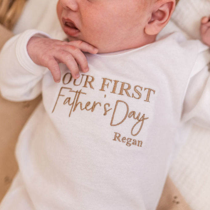 White baby sleepsuit with 'Our First Father's Day' lettering and Regan name, long sleeves