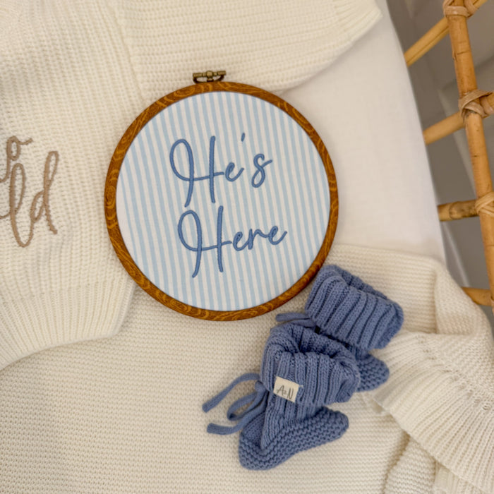 Round baby name sign, blue stripes with ‘Here’s Here’ script, brown stitched border