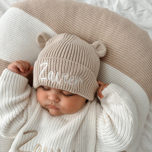 Cream knitted baby hat with bear-ear sides and embroidered name front