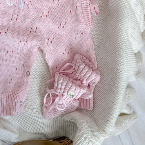 Pink knitted baby booties with ribbon bow tie and folded cuff