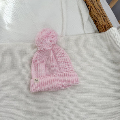 Pink knit baby hat with pom-pom top, ribbed cuff brim